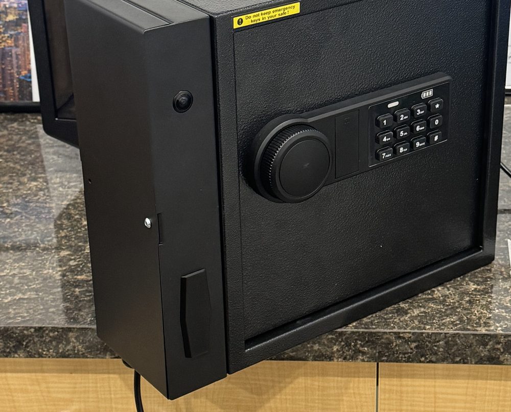 Two black wall-mounted key safes with keypad entry, sitting on a stone counter.